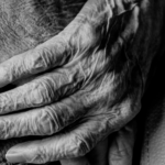 black and white photo of two people holding hands, zoomed in on their hands